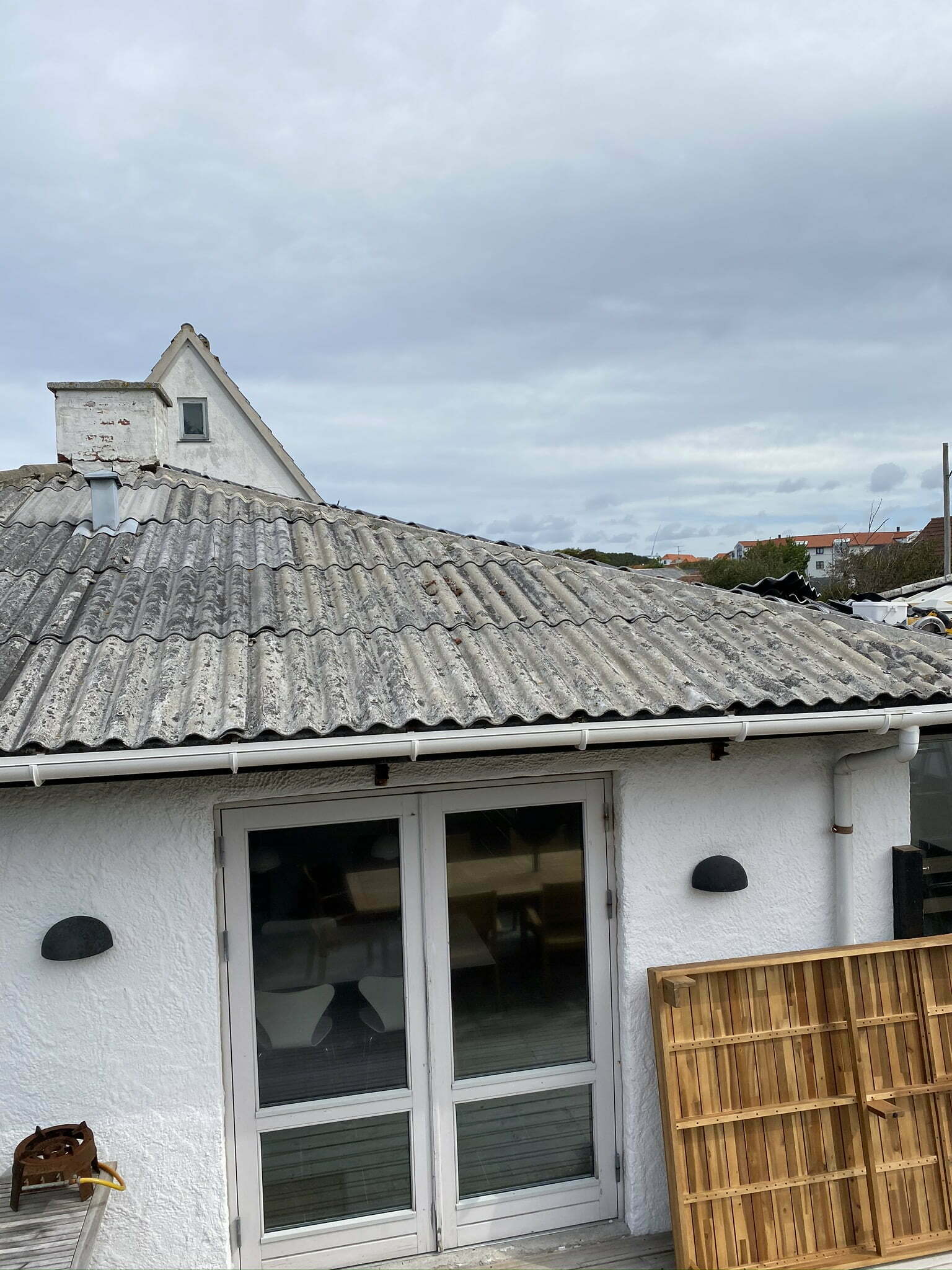 Hvidt hus med bølgeeternittag og terrasse