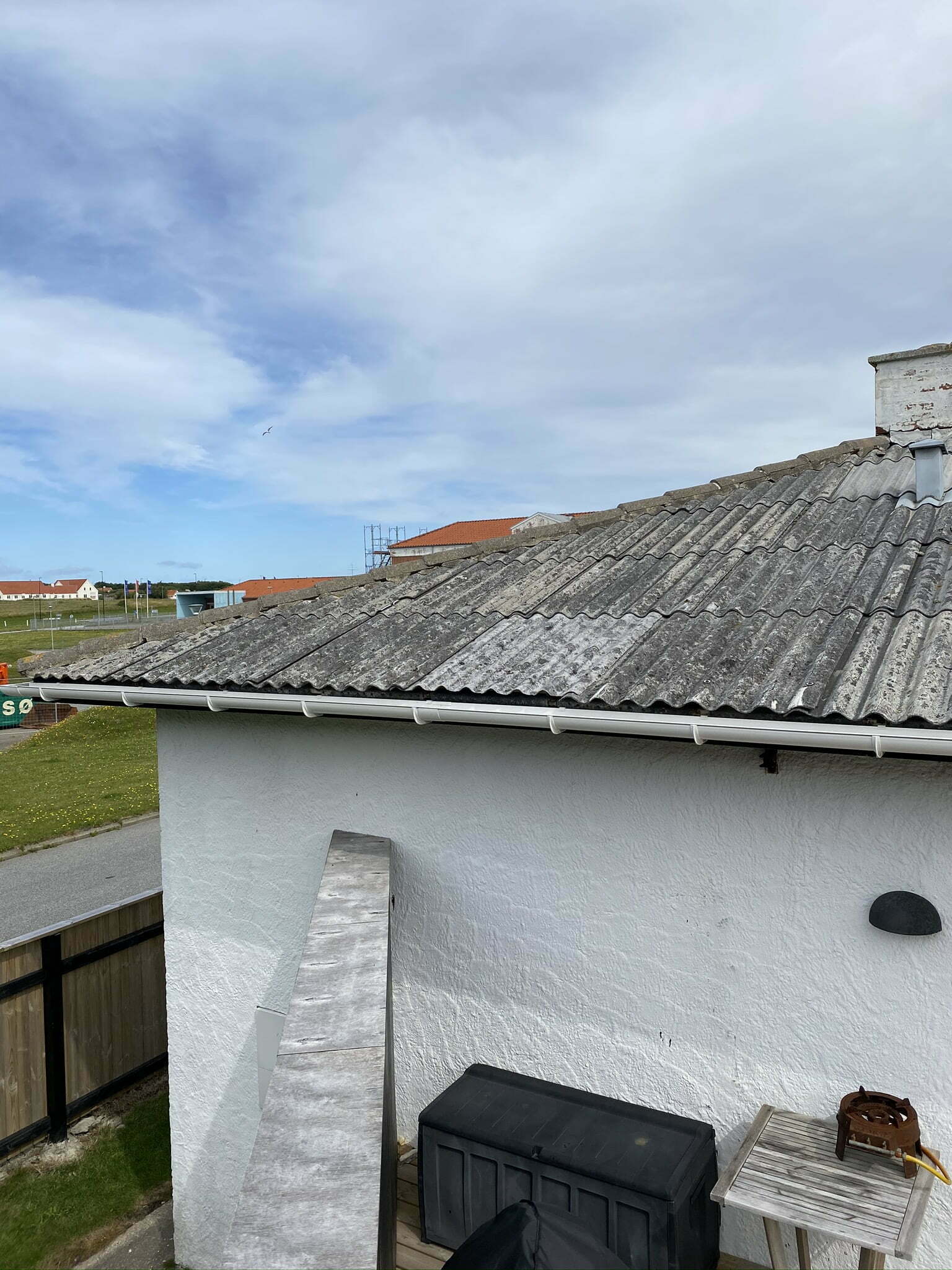 Hus med bølgeeternittag og hvid mur i kystby