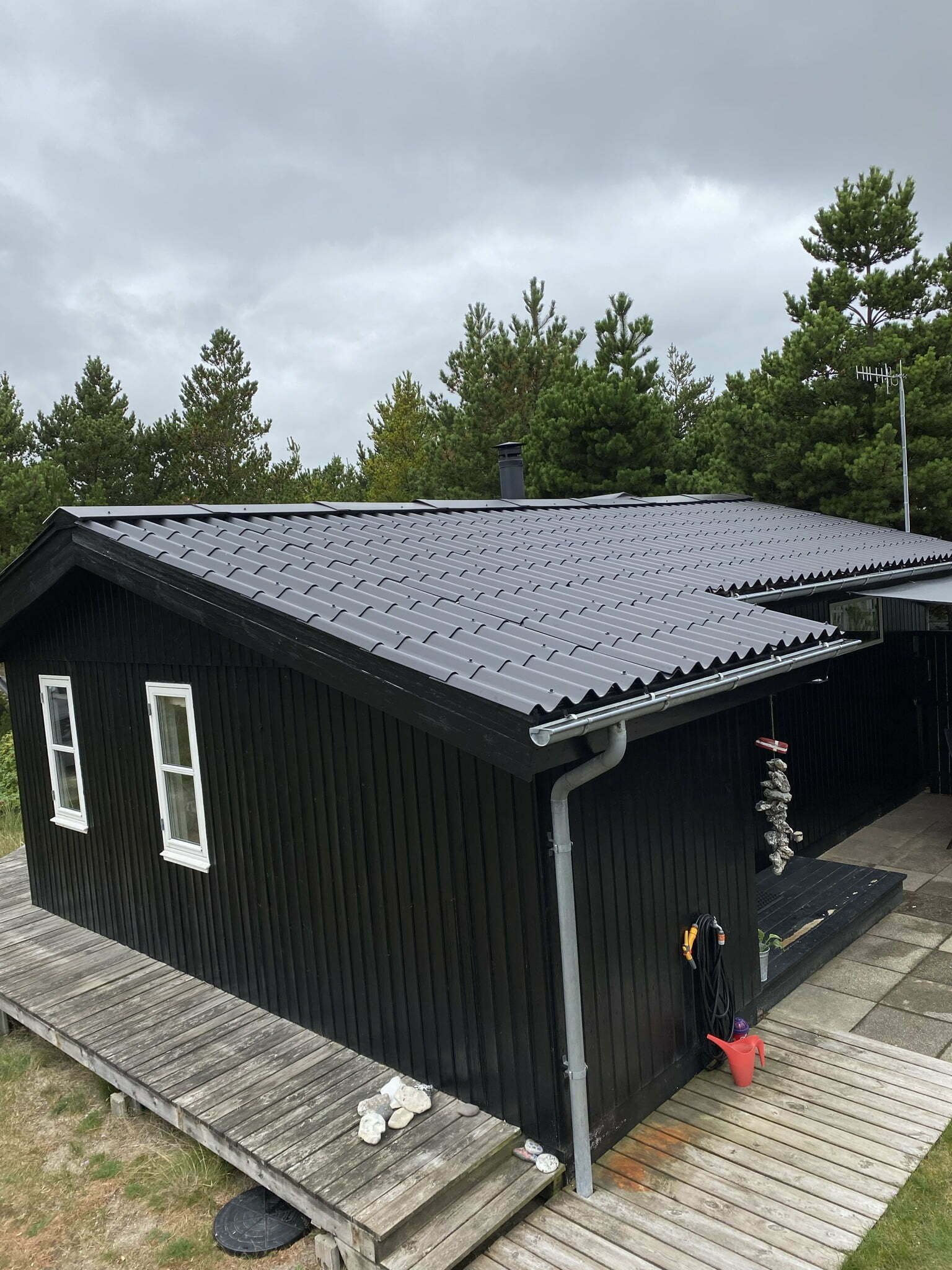 Sort træsommerhus med terrasse i skovområde